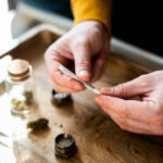 Close-up of a unrecognizable man’s hands preparing a joint of marijuana.